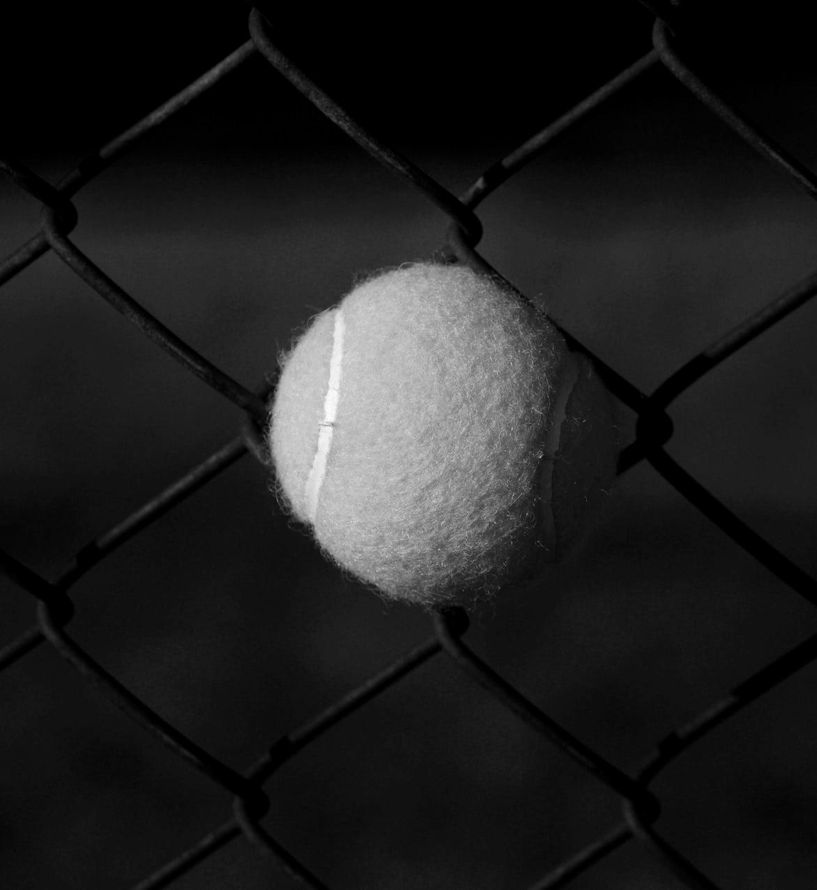 red tennis ball on gray steel fence